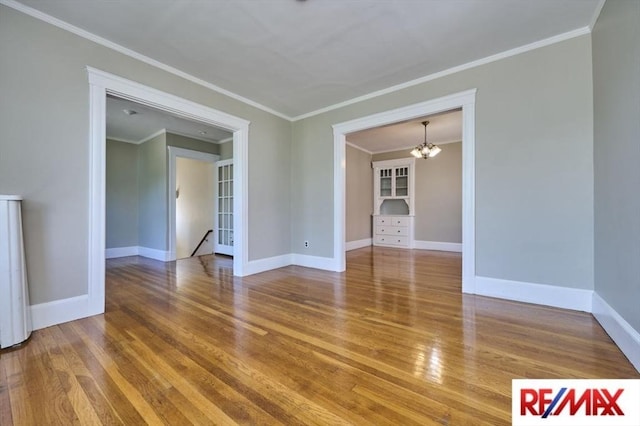 150 Nonantum St, Boston, MA 02135 - spare room featuring wood finished floors, a chandelier, baseboards, and crown molding