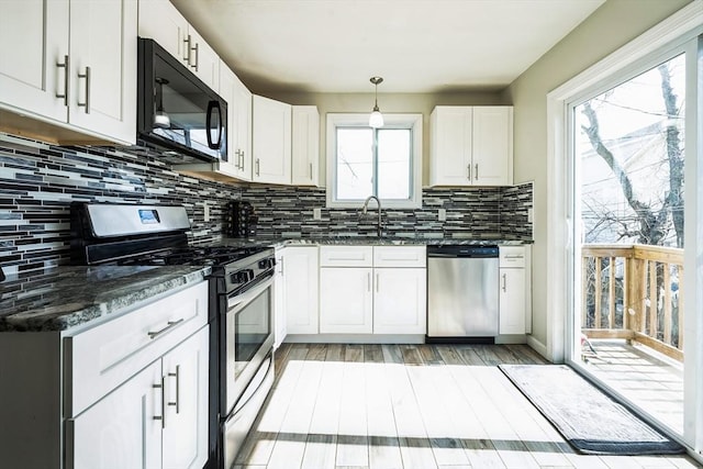 kitchen featuring backsplash, dark stone countertops, light wood-style flooring, stainless steel appliances, and white cabinetry