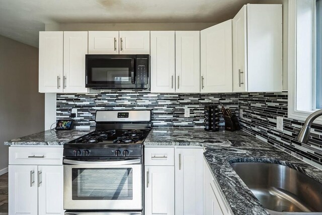 kitchen featuring gas stove, dark stone counters, a sink, decorative backsplash, and black microwave