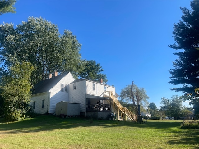 back of property featuring a lawn and a storage unit