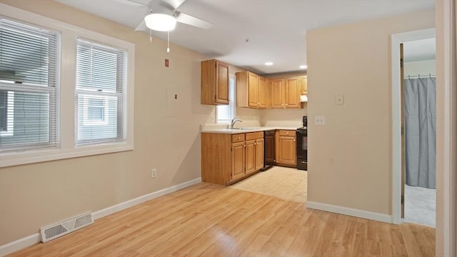 kitchen with light wood finished floors, baseboards, light countertops, black appliances, and ceiling fan