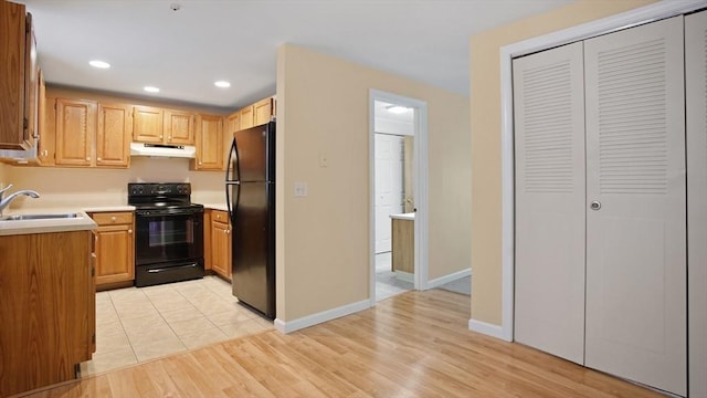 kitchen featuring black appliances, under cabinet range hood, a sink, recessed lighting, and light countertops