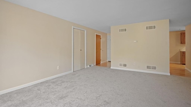 unfurnished room featuring light carpet and baseboards