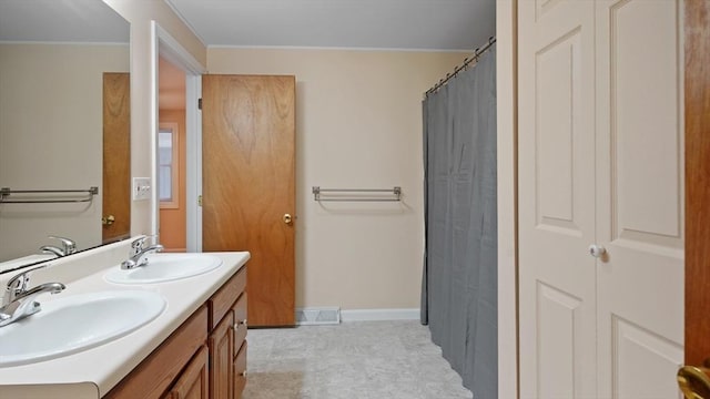 full bathroom featuring double vanity and baseboards