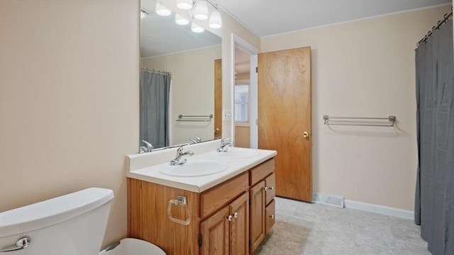 full bath with toilet, double vanity, and baseboards