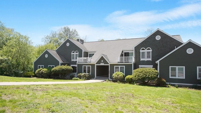 shingle-style home featuring a balcony and a front yard