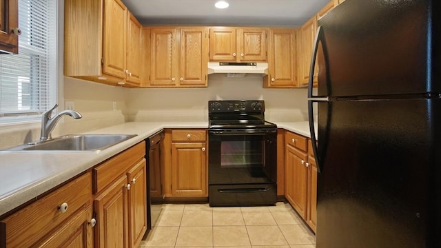 kitchen with black appliances, under cabinet range hood, a sink, light tile patterned floors, and light countertops