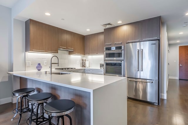 kitchen featuring appliances with stainless steel finishes, dark hardwood / wood-style floors, kitchen peninsula, and a breakfast bar area