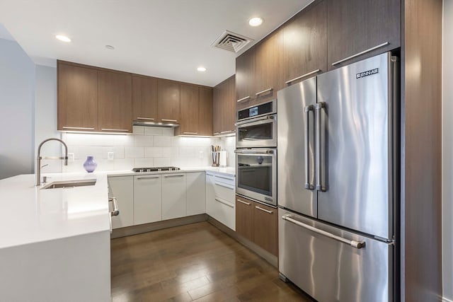 kitchen featuring white cabinetry, stainless steel appliances, sink, decorative backsplash, and dark hardwood / wood-style floors