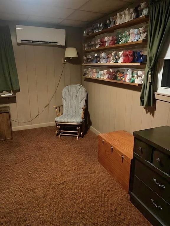 sitting room featuring a wall mounted AC, carpet, a paneled ceiling, and baseboards