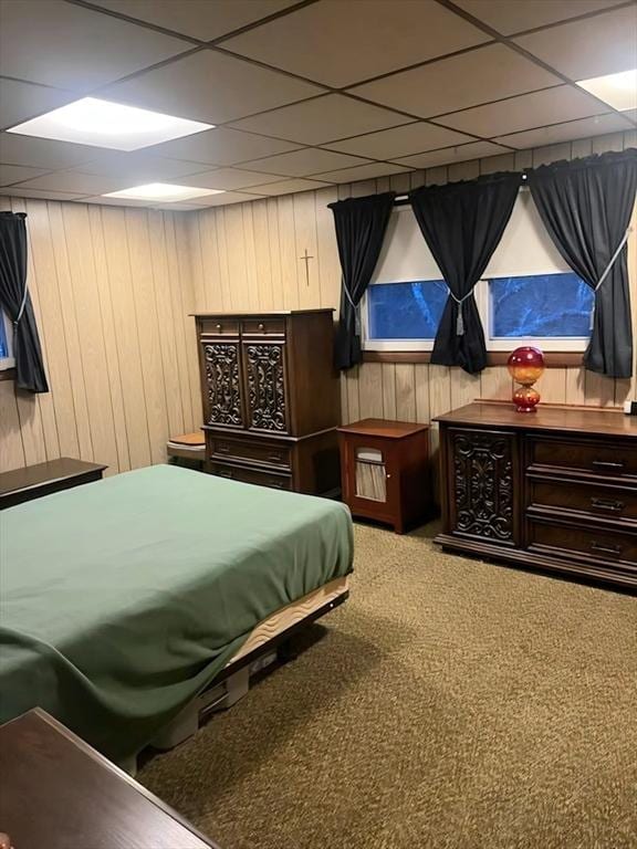 bedroom featuring a drop ceiling and wooden walls