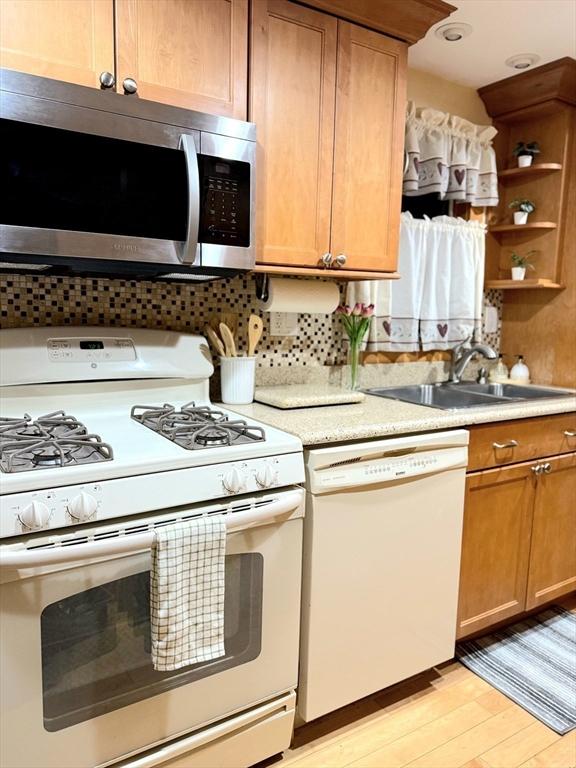 kitchen with white appliances, light wood finished floors, light countertops, open shelves, and a sink