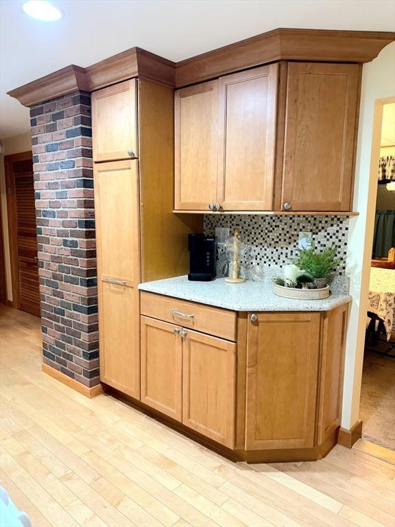 bar with light wood-type flooring and backsplash