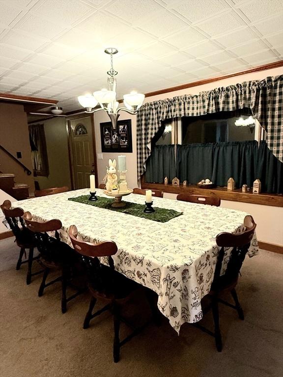 dining area featuring carpet floors, stairway, baseboards, and a chandelier