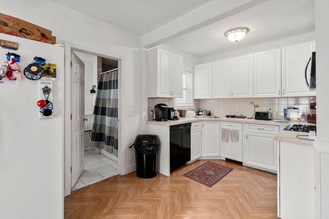 381 Hunnewell St Unit 381, Needham, MA 02494 - kitchen with black appliances, white cabinetry, light countertops, backsplash, and a sink