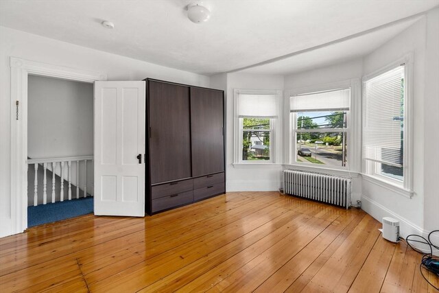 381 Hunnewell St Unit 381, Needham, MA 02494 - unfurnished bedroom featuring radiator, multiple windows, light wood-style floors, and baseboards