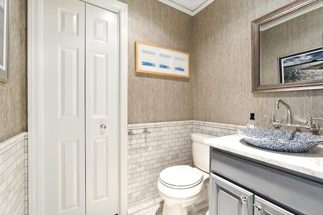 bathroom featuring vanity, a wainscoted wall, wallpapered walls, a closet, and toilet