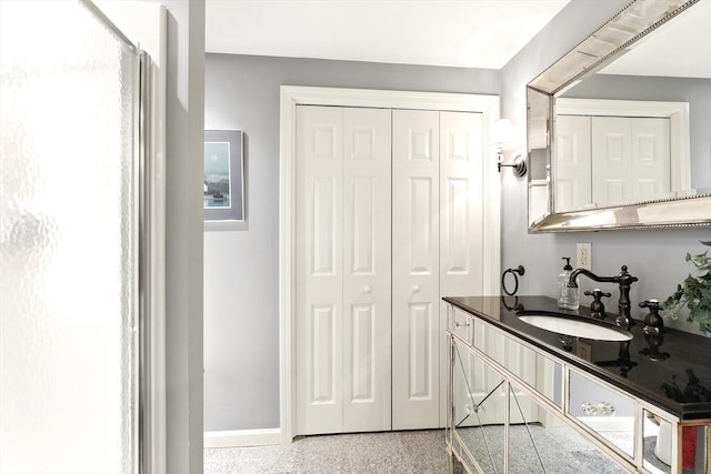 bathroom with speckled floor, baseboards, a closet, and a sink