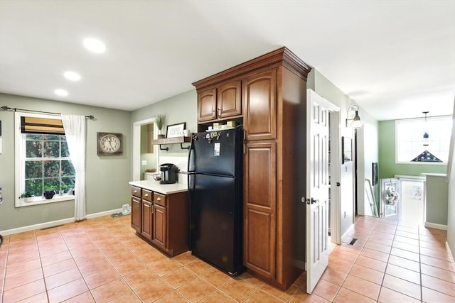 kitchen featuring visible vents, baseboards, light tile patterned flooring, freestanding refrigerator, and light countertops