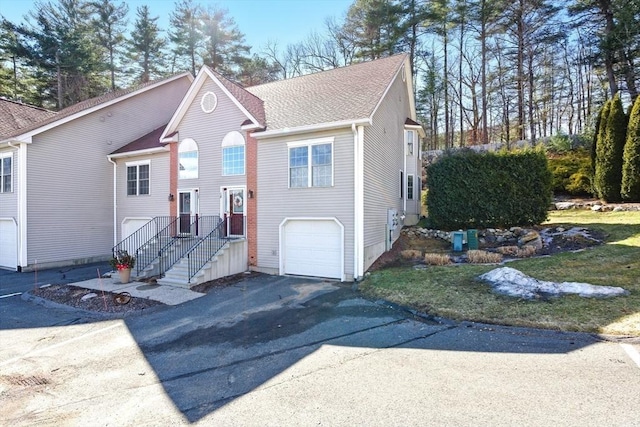 bi-level home featuring driveway, an attached garage, and a shingled roof