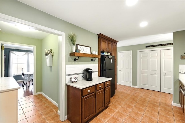 kitchen featuring tasteful backsplash, baseboards, light tile patterned floors, freestanding refrigerator, and open shelves