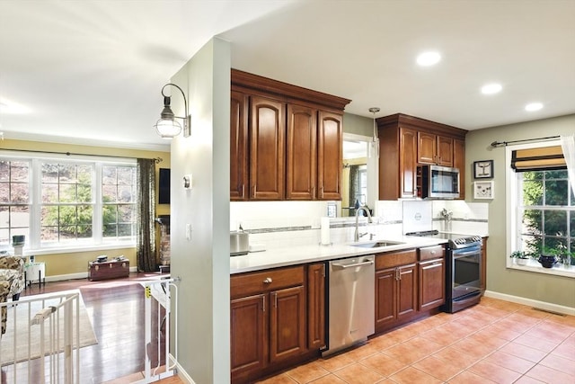 kitchen with a sink, stainless steel appliances, backsplash, and a wealth of natural light