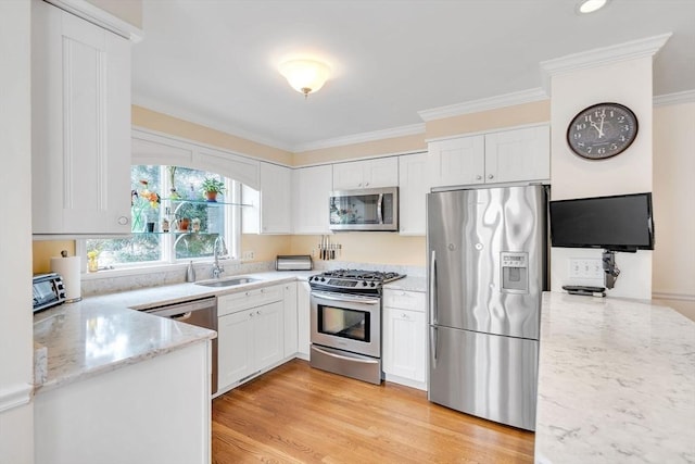 kitchen featuring a sink, stainless steel appliances, white cabinets, crown molding, and light stone countertops