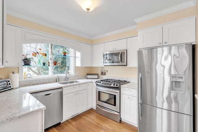 kitchen with crown molding, white cabinets, appliances with stainless steel finishes, and a sink