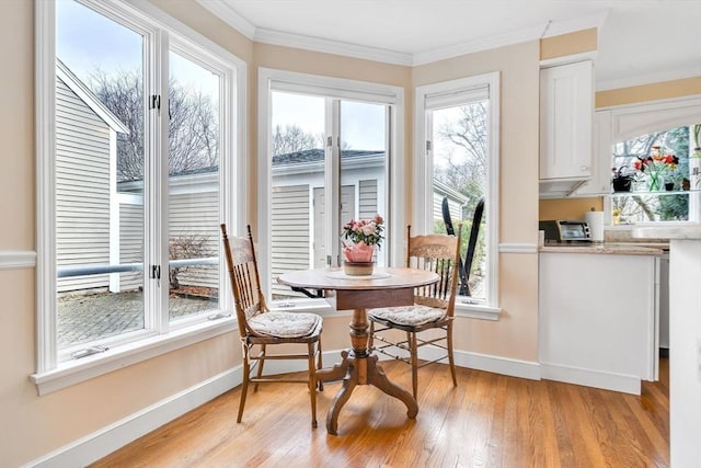 dining space with light wood-type flooring, crown molding, and baseboards