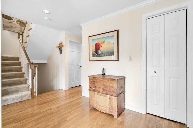 corridor with stairs, light wood-type flooring, baseboards, and ornamental molding