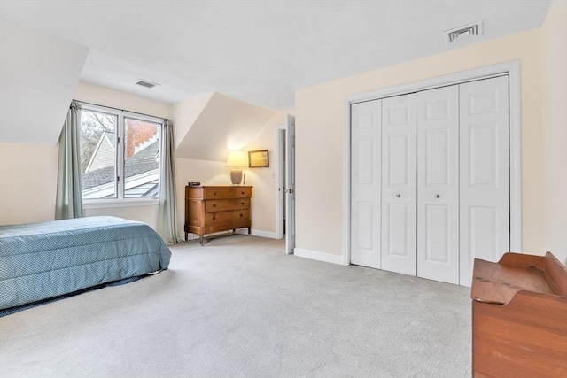 carpeted bedroom with lofted ceiling, baseboards, visible vents, and a closet