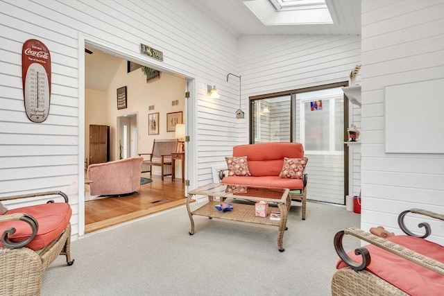 interior space featuring a skylight, carpet flooring, and wood walls