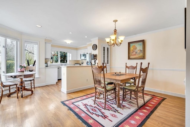 dining area featuring baseboards, light wood-type flooring, an inviting chandelier, and ornamental molding