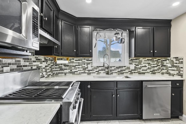 kitchen featuring dark cabinetry, light countertops, stainless steel appliances, and a sink