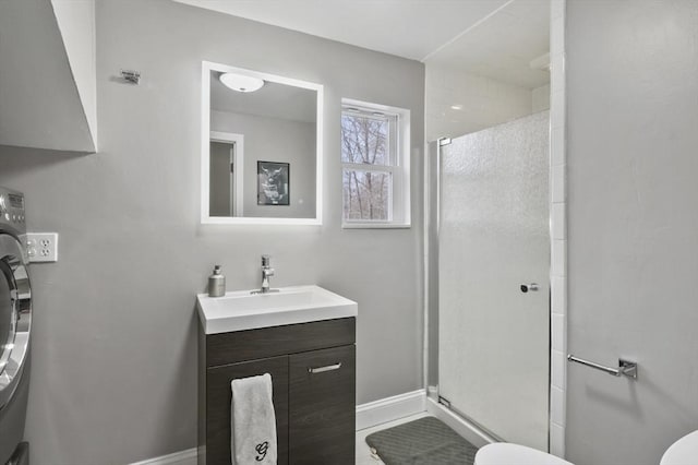 bathroom featuring washer / clothes dryer, toilet, a stall shower, and vanity