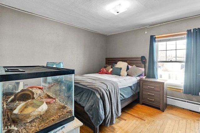 bedroom with a baseboard heating unit and light parquet floors