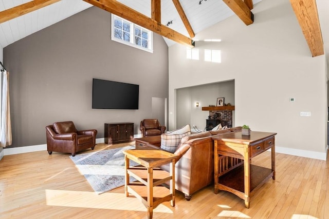 living room featuring beamed ceiling, light wood-type flooring, high vaulted ceiling, and a fireplace