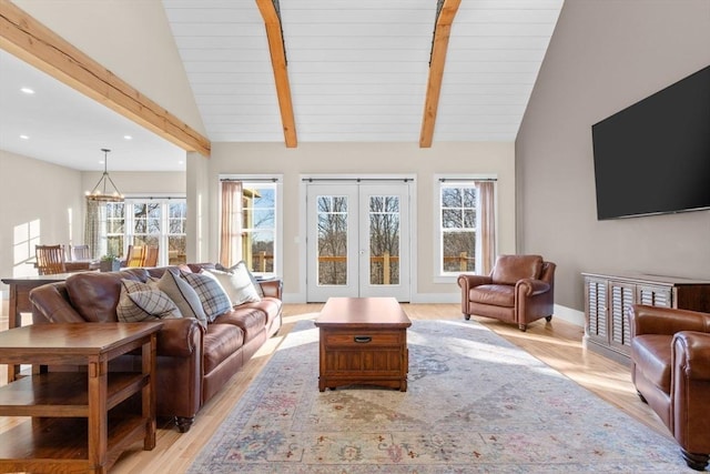 living room featuring vaulted ceiling with beams, french doors, light wood-type flooring, and a notable chandelier