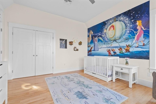 bedroom featuring a crib, hardwood / wood-style floors, a closet, and ceiling fan