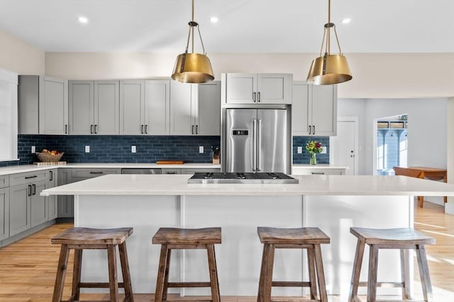 kitchen with gray cabinetry, decorative backsplash, a kitchen island, and stainless steel appliances