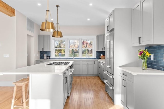 kitchen with gray cabinetry, decorative backsplash, and a center island