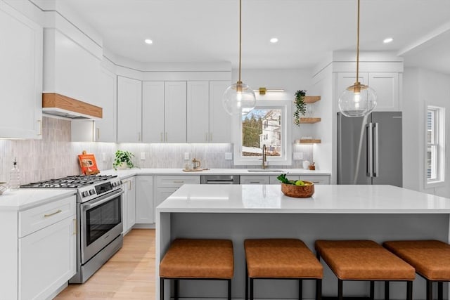 kitchen with white cabinetry, appliances with stainless steel finishes, pendant lighting, and a kitchen bar