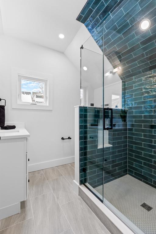 bathroom with a shower with door, vanity, and lofted ceiling