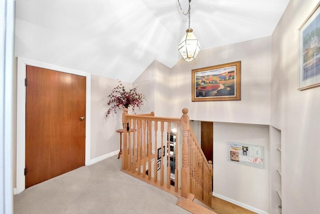 hallway featuring an upstairs landing, carpet floors, vaulted ceiling, baseboards, and a chandelier