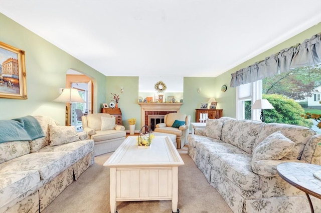 living room with light carpet, arched walkways, and a fireplace