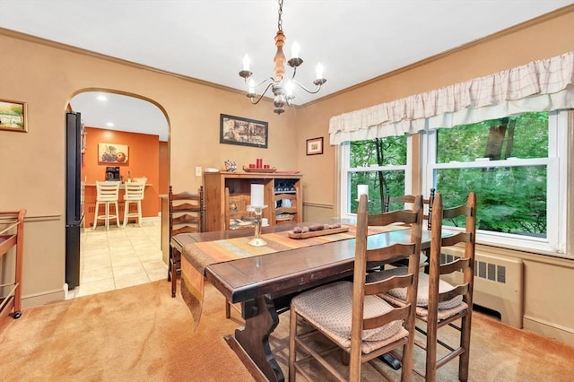 dining room featuring arched walkways, light colored carpet, a chandelier, ornamental molding, and baseboards