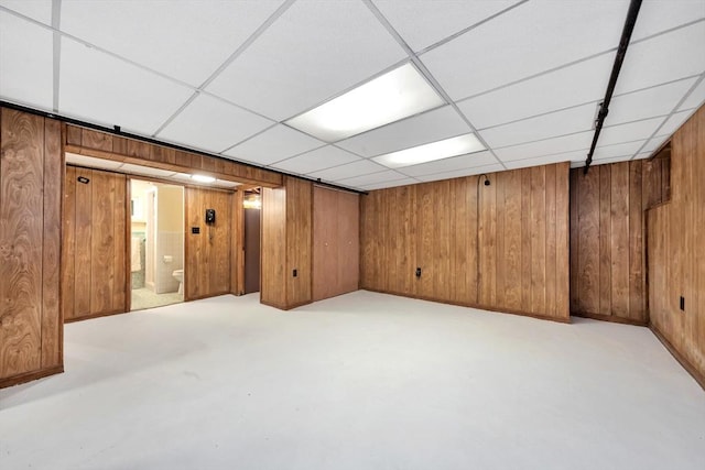finished below grade area featuring wooden walls and a paneled ceiling