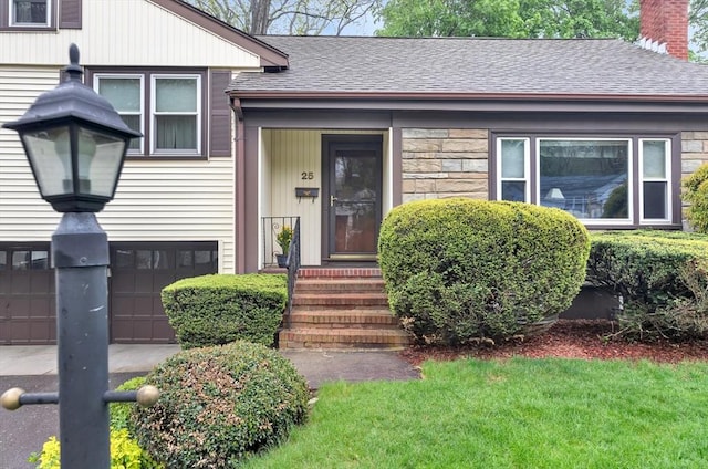 entrance to property with a shingled roof, a chimney, an attached garage, stone siding, and a lawn