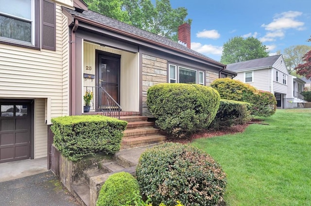 view of exterior entry featuring a chimney, a lawn, and stone siding