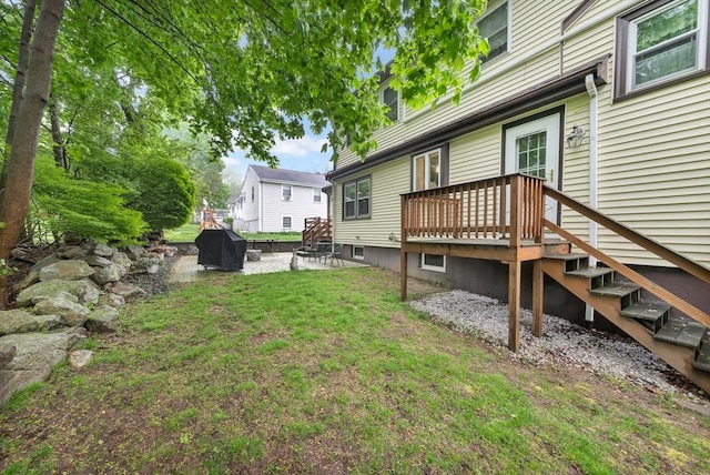 view of green lawn featuring a wooden deck, stairs, and a patio